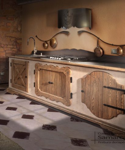 Bancone cucina in legno stile finta muratura, con ante in castagno sagomate e piano e attacca rame in ferro battuto.